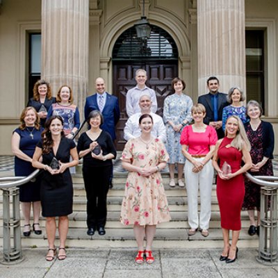 A group of people standing on the steps of a building holding awards.